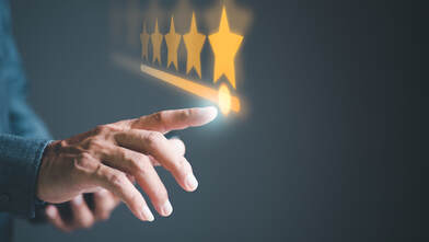 Image of a man's hand moving across a set of stars on a large touch screen, he's choosing five stars indicating he's giving an excellent review to a company. Helping customers trust your business is a service of 4-Good Writing.