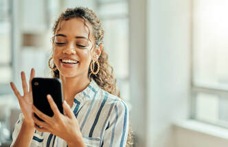 Image of a young woman smiling and appearing to discover something delightful on her smartphone. Helping customers find you on the internet via SEO is a service of 4-Good Writing.